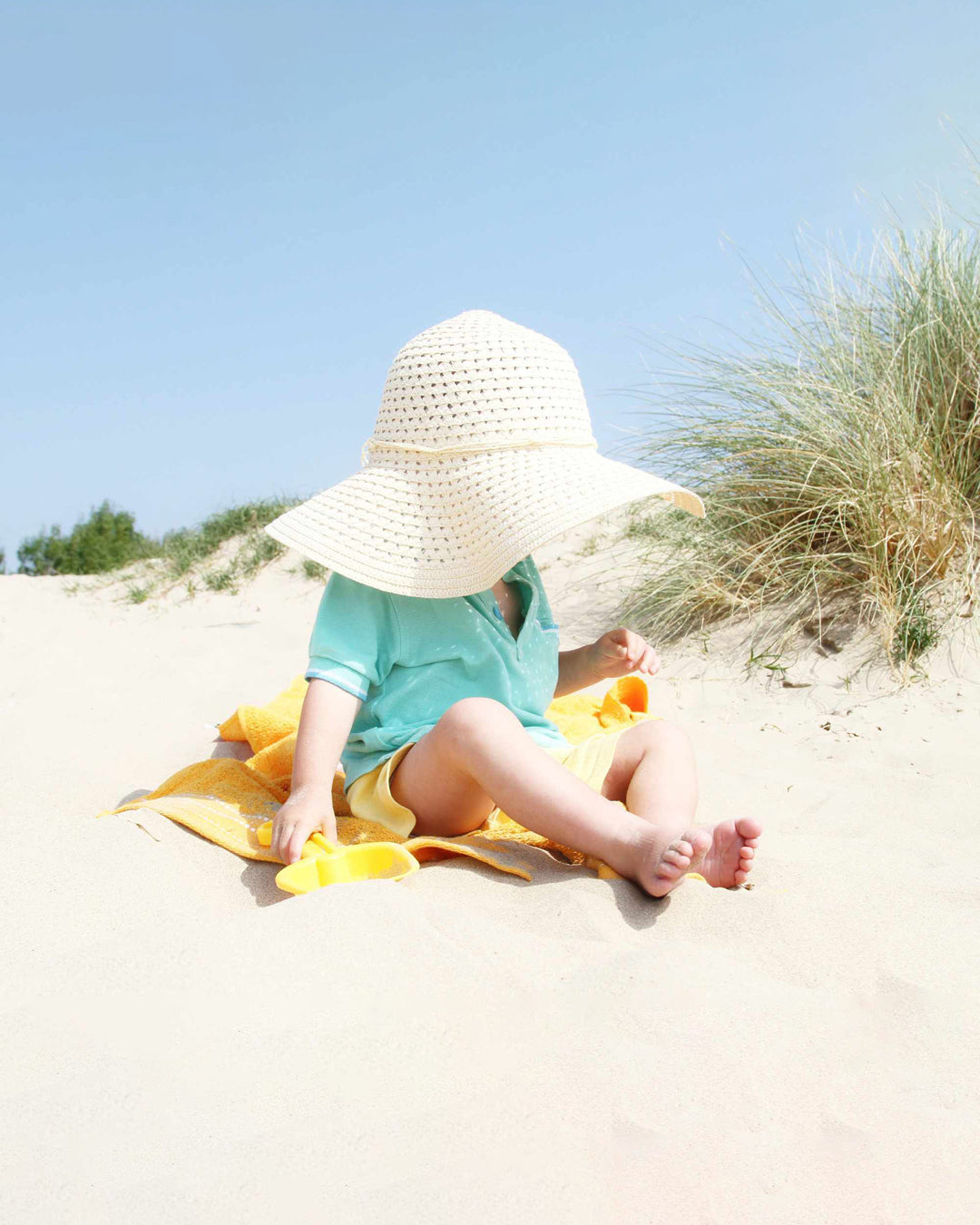 Baby in a big hat on the beach