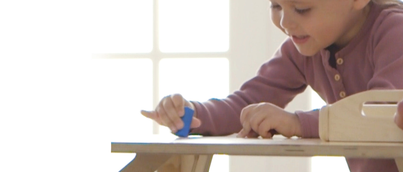 Child holding blue crayon coloring